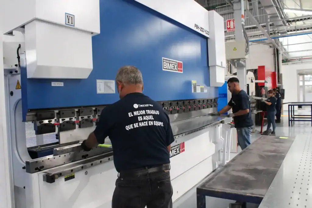 Proceso de fabricación de charolas metálicas en la planta de Tecnotray, donde técnicos especializados operan maquinaria de precisión para producir sistemas de canalización eléctrica industrial certificados.