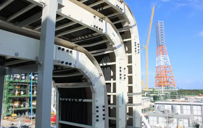 Charola tipo escalera instalada en entorno industrial, mostrando estructura curva y soporte para canalización eléctrica en obra.