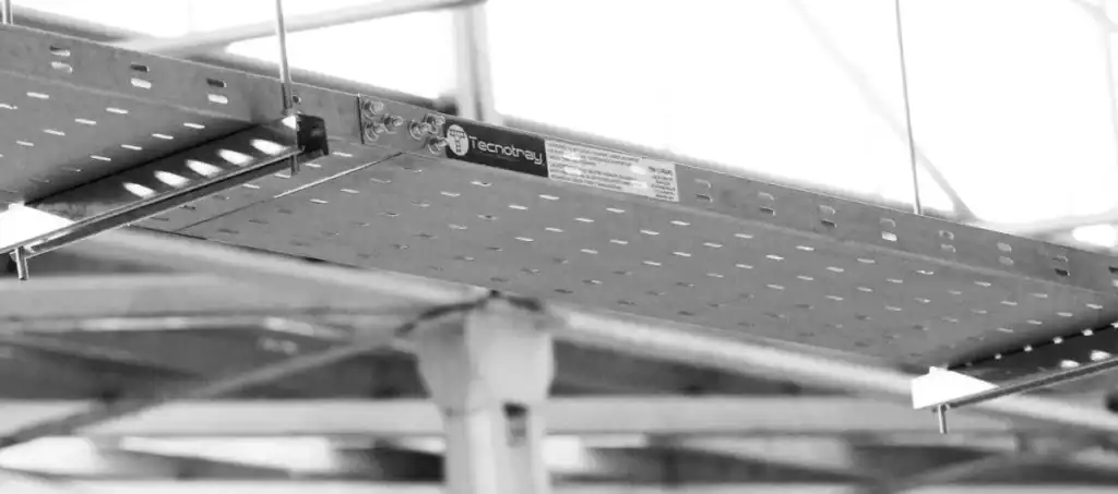 Charola tipo marino instalada en una estructura industrial, diseñada para facilitar el drenaje de agua y resistir humedad, garantizando durabilidad y seguridad en instalaciones eléctricas expuestas.